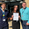 Alex, Kim, and Steve standing together. Kim is holding a certificate that recognises Danesgate's Asthma Friendly School accreditation.